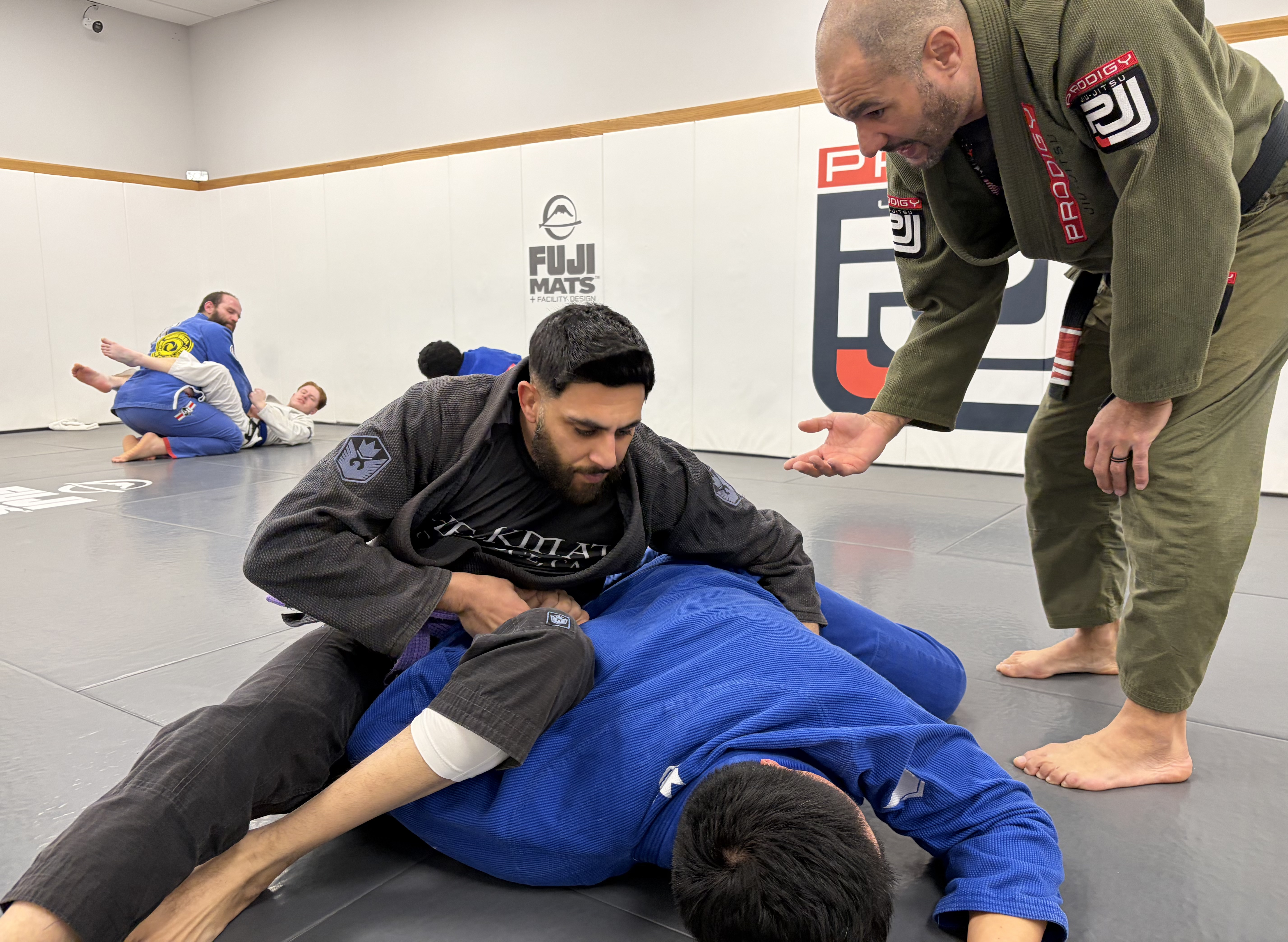 Prodigy Jiu-Jitsu coach giving one-on-one instruction to a student on the mat